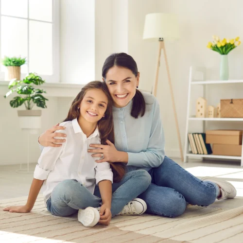 smiling-mom-daughter-sitting-on-floor Smiling mother & young daughter sitting on the floor